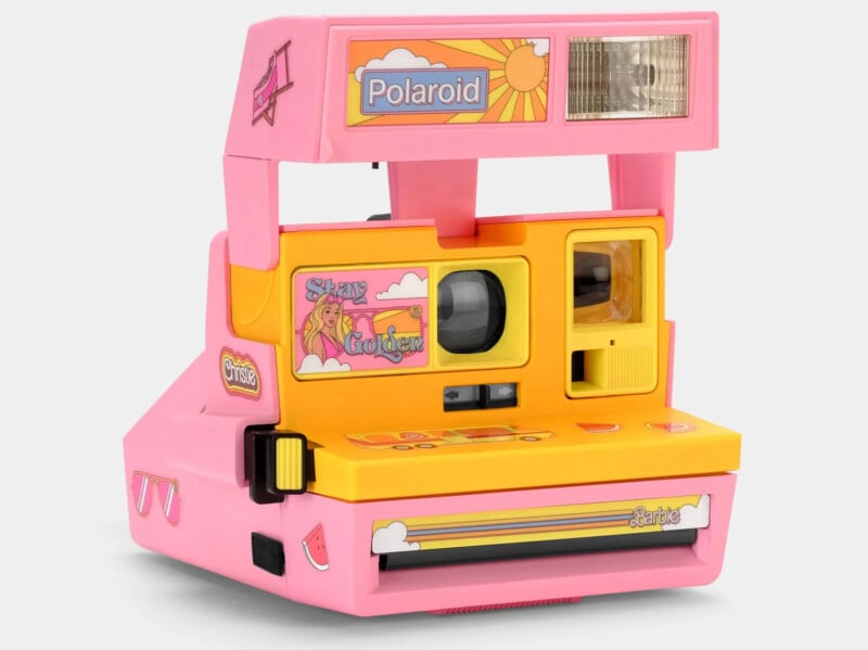 A retro-style Polaroid instant camera in vibrant pink and yellow colors. It features graphic designs including a woman on a cloud with a rainbow and the text "Stay Golden." The flash is positioned above the lens, and the overall design is playful and nostalgic.