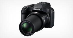 A black Panasonic Lumix DC Vario camera with extended zoom lens, showing detailed features such as control dials, buttons, and a built-in flash on a white background. The lens is marked 60X optical zoom and 3.3-6.4/20-1200 ASPH.