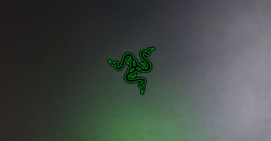 A gray surface features a bright green logo of three intertwined snakes forming a symmetrical design, commonly associated with the Razer brand. The overall appearance is sleek and modern.