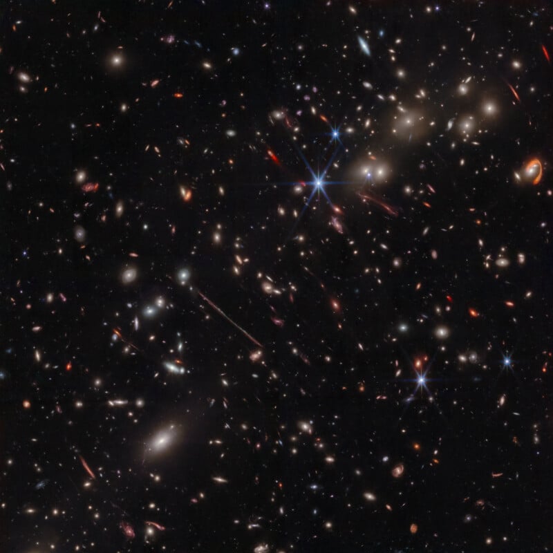 Dense fields of stars and galaxies of various shapes and sizes are scattered across the darkness of space: some stars shine brightly with noticeable diffraction spikes, while many galaxies look like smudges or glowing specks.