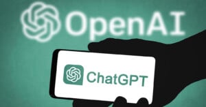 A hand is holding a smartphone displaying the ChatGPT logo and text on its screen. In the background, the OpenAI logo and text are visible. The colors scheme consists of green and white tones.