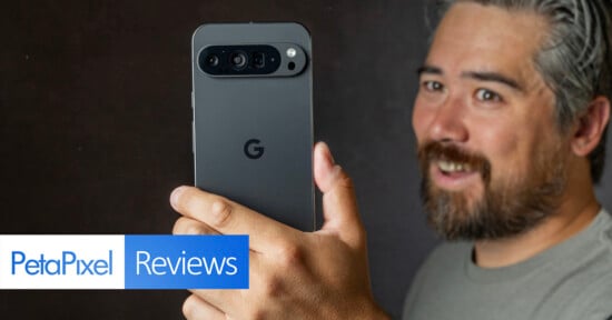 A person holds up a Google Pixel smartphone facing the camera. The phone's camera array is visible. The person has a beard, mustache, and gray hair. "PetaPixel Reviews" is prominently displayed in text on the left side of the image.