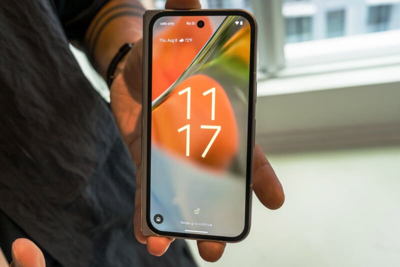 A person holds a smartphone displaying the time as 11:17 on Thursday, August 8. The phone screen has a colorful abstract background, and the notification bar at the top shows "calls only" and "hi 5." The hand holding the phone is partially visible against a blurred background.