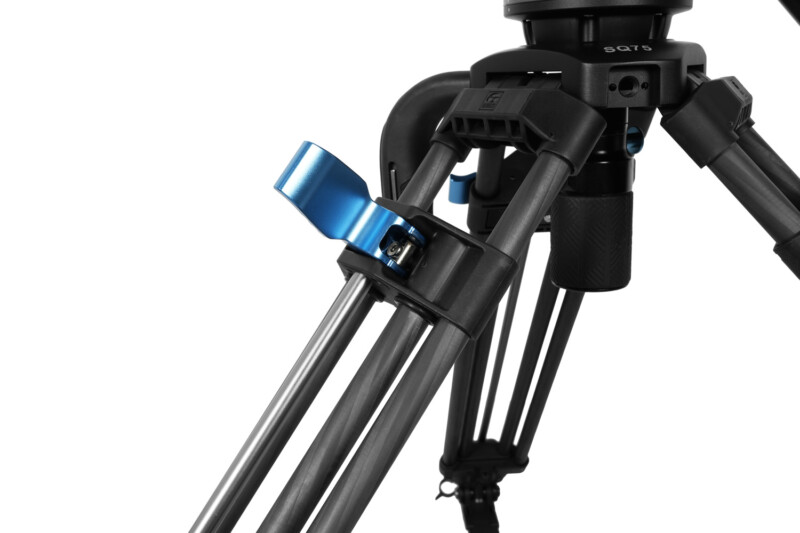 Close-up of a professional tripod, focusing on the leg lock mechanism. The tripod has a sturdy, black construction with a striking blue locking lever, providing support for photography and videography equipment. The materials appear to be high-quality metal and plastic.