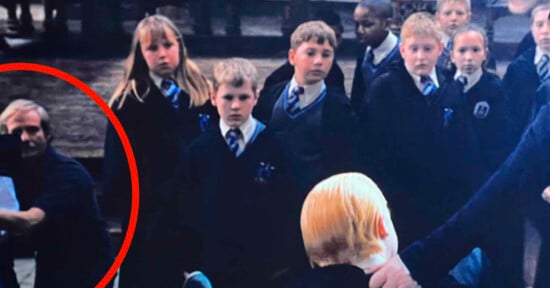 A group of schoolchildren in uniforms stand closely together, looking in various directions. One adult, partially circled in red, is positioned on the left side of the image. Another person's blonde head is visible in the foreground.