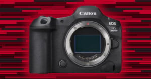 A Canon EOS R5 Mark II camera body against a red and black striped background. The camera is shown without a lens attached, and the sensor is visible. It has a textured grip on the right side and several buttons and dials on the top and back.