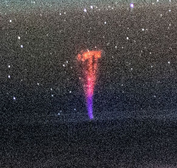 A bright red and purple vertical streak of light stands out against a starry night sky. The streak, called a sprite, is a type of transient luminous event that occurs high in the atmosphere.