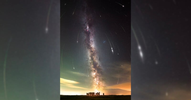 A stunning night sky photograph featuring the Milky Way galaxy stretching vertically above the ancient stone circle of Stonehenge. Streaks of meteors and stars accentuate the clear, dark sky, creating a breathtaking celestial scene.