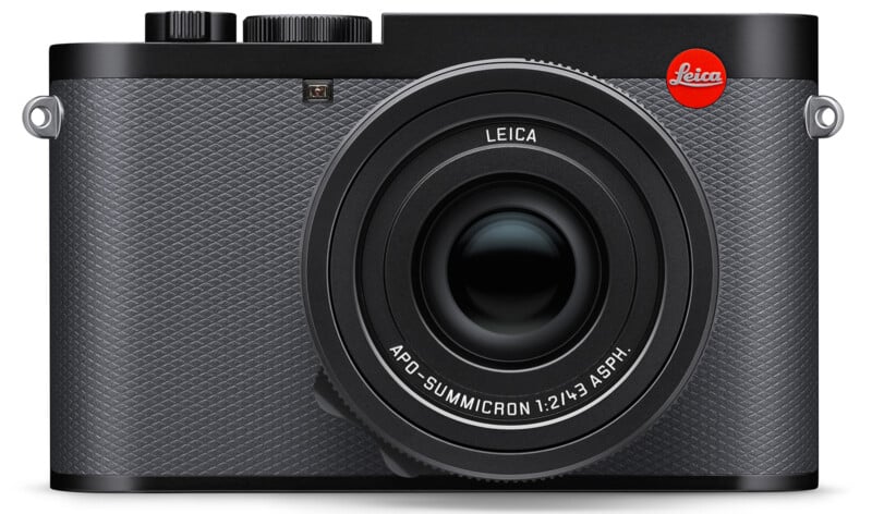 A high-end Leica Q2 digital camera is shown from the front. The camera has a textured black body, a large lens with "APO-Summicron 1:2/43 ASPH." inscribed, and the distinctive red Leica logo on the top right.