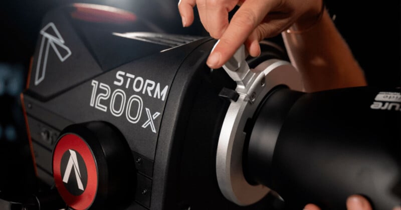 Close-up of a person adjusting a control knob on a black Aputure Storm 1200X professional studio light. The light features a sleek, modern design with visible branding and technical details. The image highlights the interaction with the equipment.