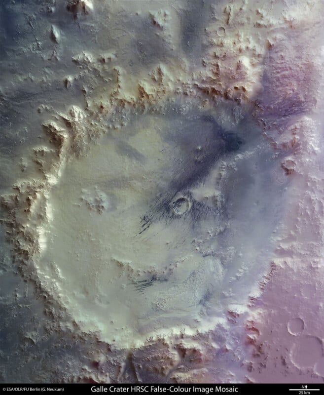 A high-resolution image of Galle Crater on Mars, depicted in false color. The crater has a distinctive circular formation with varying shades of purple, blue, and green, highlighting terrain features. Jagged ridges and smooth plains are visible within and around the crater.