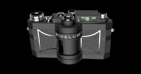 A black Widelux panoramic film camera with silver accents, featuring multiple dials and controls on the top. The camera has a distinctive cylindrical lens in the center for wide-angle photography, set against a black background.