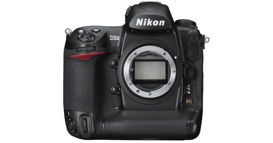 A black Nikon D3X DSLR camera body is shown without a lens attached. The camera features various buttons and dials, a prominently displayed Nikon logo on the pentaprism, and a centered lens mount showing the camera's sensor.