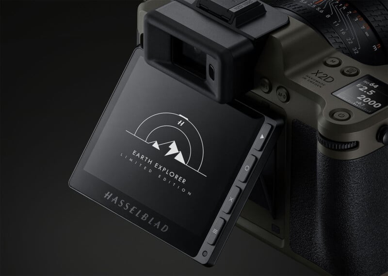 Close-up view of a digital camera displaying a logo reading "Earth Explorer Limited Edition" with a mountain graphic on its screen. The camera has a flip-out screen and a rugged design with visible control buttons and dials. The hashtag "#HASSELBLAD" is at the bottom of the screen.