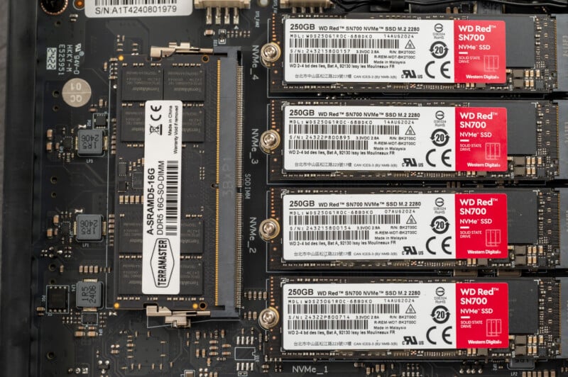 Close-up of a computer motherboard displaying one TEAMGROUP SSD and four WD Red SN700 250GB NVMe SSDs installed in their respective slots. The image focuses on the intricate details and labeling of the solid-state drives and the surrounding circuitry.