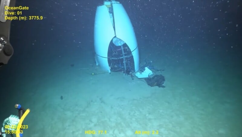 A deep-sea exploration submersible sits on the ocean floor at a depth of 3775.9 meters. The submersible's hull appears damaged. The screen displays various readings, including the date, time, heading, and altitude of the sub.