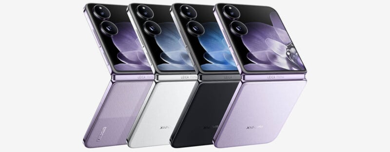 Four foldable smartphones are shown partially open, with each having a different back cover color: pastel purple, white, black, and lavender. The screen displays a close-up image of a flower. Each phone has a dual camera setup on the upper back.