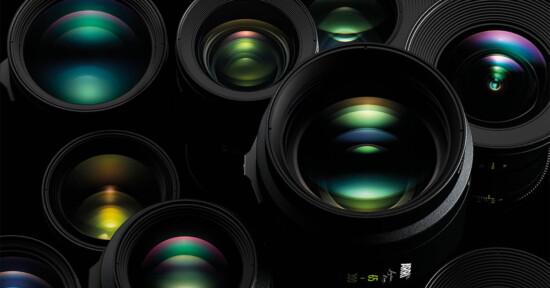 A close-up image of various camera lenses positioned at different angles. The lenses display colorful reflections and light flares, showcasing the intricate glass elements inside. The overall color palette includes deep blacks and vibrant greens, blues, and purples.