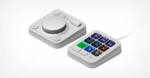 A photo shows a two-part control pad on a white background. On the left is a gray rectangular dial pad with a large round dial and three buttons. On the right is a smaller rectangular keypad with nine colorful, programmable buttons, each with different application icons.