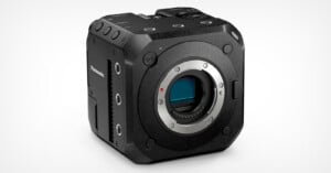 A black, box-shaped Panasonic camera body with a lens mount, numerous buttons, and ports. The camera has a rugged, slightly textured surface and is angled towards the right, showcasing its compact design and professional build.