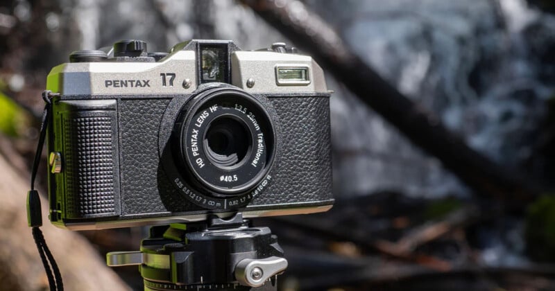 Close-up of a vintage Pentax camera mounted on a tripod. The lens reads "ASAHI PENTAX 45mm f/4.5 1:2-3.5 zoom (modular)." The background is blurred, showcasing an outdoor, natural setting with flowing water and foliage.