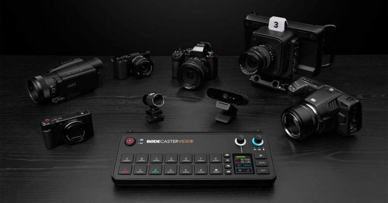 A collection of professional video production equipment is displayed on a black surface. Central to the arrangement is the RODECaster Video console, surrounded by various cameras, lenses, and a 4K camcorder, all set against a dark background.