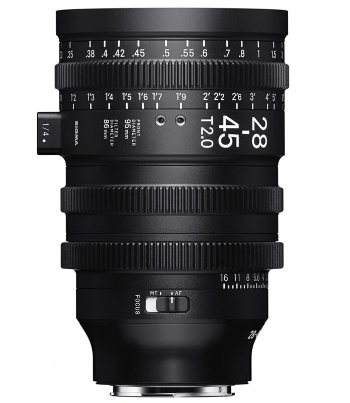 A black Sigma 28-85mm T2.0 camera lens is shown. It features various focus and aperture markings, a focus ring, and toggle switches for manual and autofocus modes. The lens has a complex design with multiple rings for precise adjustments.