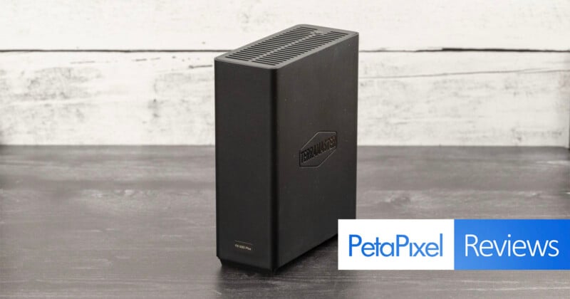 A black external hard drive sits on a wooden table against a white-washed wooden backdrop. The hard drive has the logo "TerraMaster" printed on it. A banner at the bottom reads "PetaPixel Reviews" in blue and white text.