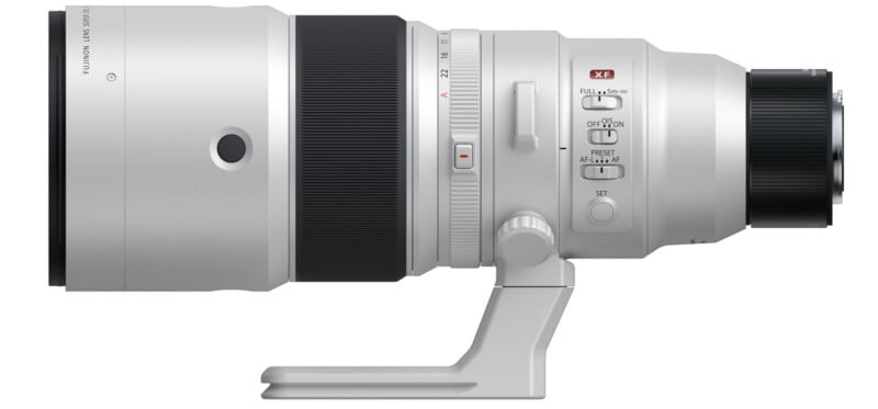 A white Fujifilm lens with various controls and a tripod mount. The lens features a zoom adjustment ring, focus preset, and stabilization switches. It is designed for high-performance photography with a large front element.