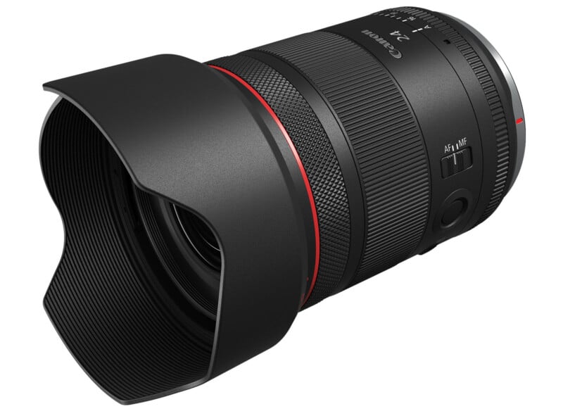 A black camera lens with a lens hood attached, featuring a red ring near the front. The lens has a zoom ring, focus ring, and switches labeled "AF/MF." The brand name and specifications are partially visible. The background is white.