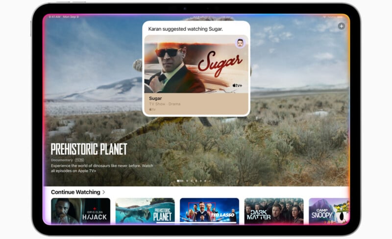 A tablet displaying a streaming app interface with a suggestion for the TV show "Sugar" featuring a man in sunglasses. Below, various show recommendations like "Prehistoric Planet" and "Ted Lasso" are visible on the home screen.