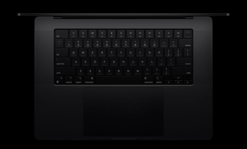 A top-down view of a black laptop with a backlit keyboard on a black background. The screen is slightly open, and the touchpad is visible below the keyboard.