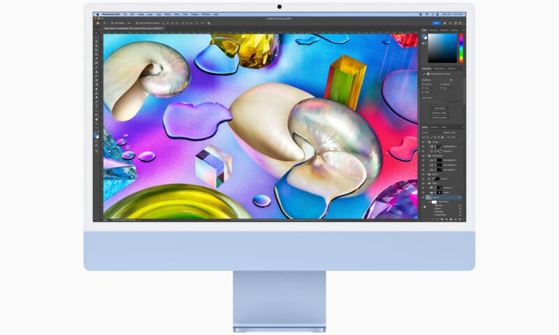 A computer monitor displaying a colorful abstract digital artwork featuring various geometric shapes, spheres, and textures in bright tones. The screen shows graphic design software with editing tools and layers visible on the side.