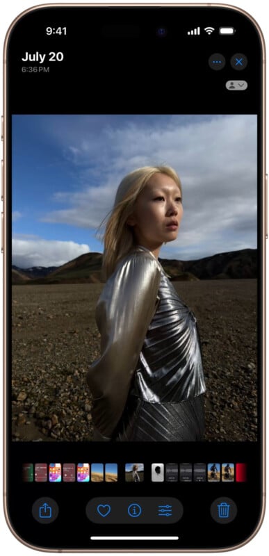 A smartphone display shows a photo of a person wearing a shiny silver top, standing outdoors on a rugged landscape under a partly cloudy sky. The top menu shows the date July 20 at 6:36 PM. App icons are visible at the bottom of the screen.