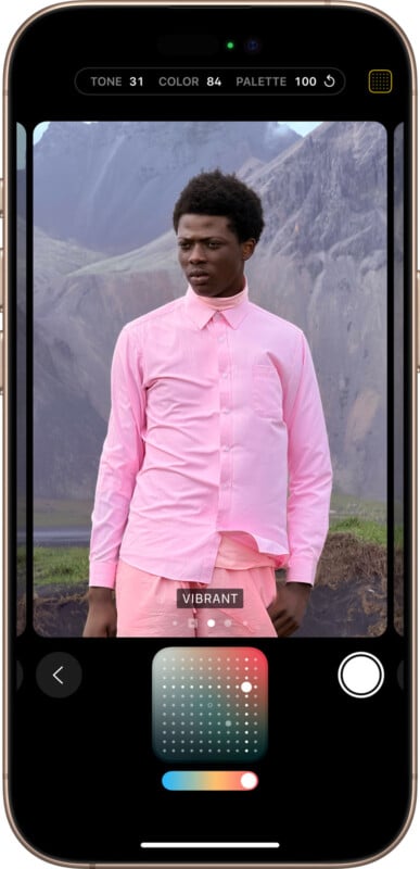 A smartphone screen displays a photo of a person wearing a pink shirt and pants, standing outdoors in a mountainous landscape. The image editing interface shows options for adjusting tone, color, and palette.