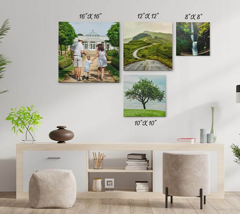 A living room with a wooden console table, plants, and two poufs. Four framed photos of various sizes are on the wall, featuring different scenes: a family walking, a winding road, a waterfall, and a lone tree.