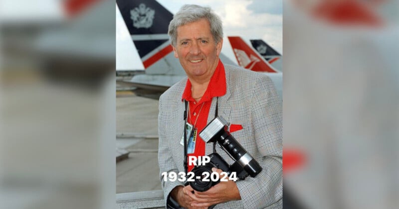 Older man smiling while holding a camera at an airport with airplanes in the background. He is wearing a gray checkered jacket and red shirt. Text below reads "RIP 1932-2024.