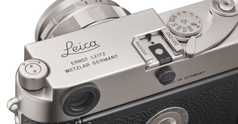 Close-up of a vintage Leica camera displaying the brand's logo and "ERNST LEITZ WETZLAR GERMANY" text. The camera features a silver top with various dials and a textured black body.