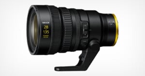 A professional NIKKOR camera lens with a range of 28-135mm and power zoom, featuring various adjustment dials and switches on its side, mounted on a tripod collar against a plain white background.