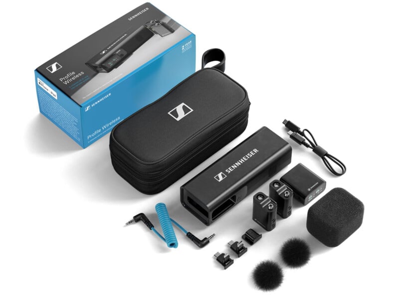 The image displays a Sennheiser wireless microphone system. Included are a microphone, receiver, carrying case, cables, attachments, and windscreens, all arranged neatly beside the product box.