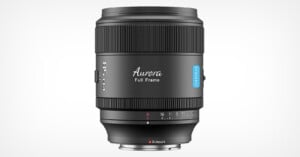 A black Aurora full-frame camera lens with blue accented detailing is shown against a white background. The aperture range is marked on the lens, and it features a silver mount at the base.