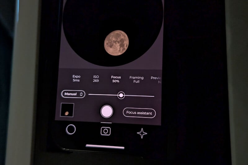 A smartphone screen showing a camera app with a photo of the moon. The app is in manual mode with options for exposure, ISO, focus, framing, and preview. A small moon icon is visible at the bottom left, with a "Focus assistant" button beside it.