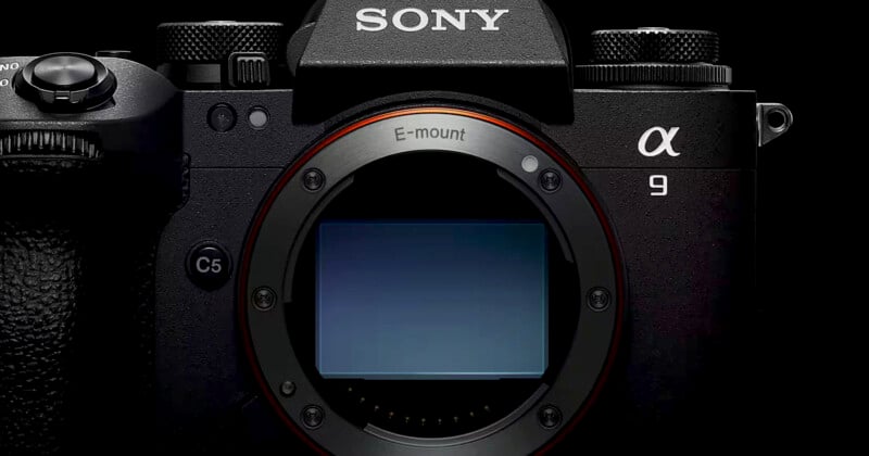 Close-up view of a Sony Alpha 9 camera body, showcasing the E-mount connection in the center. The camera is black, with textured grips and visible branding at the top. The camera is displayed against a dark background.