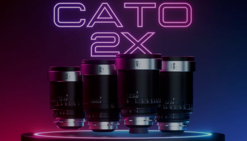 A set of four black camera lenses is displayed under neon lights with "CATO 2X" written above them in bold, glowing letters. The background has a gradient of pink and blue hues, creating a modern and futuristic look.