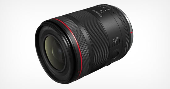 A black Canon camera lens with red detailing, featuring focus adjustment switches. The lens is positioned diagonally against a white background, showcasing its branding and sleek, cylindrical design.