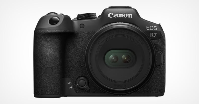 A Canon EOS R7 camera with a black body is displayed against a white background. The lens cap is on, showcasing the camera's compact design and various buttons for functionality.