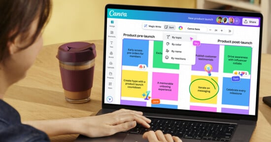 A person uses a laptop displaying a colorful project management board on Canva. The board includes sections for pre-launch and post-launch tasks, with sticky notes, tasks, and names like "June" and "Tom." A reusable coffee cup is beside the laptop.