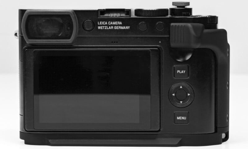 The image shows the back of a black Leica camera. It features a large LCD screen, a viewfinder, and several buttons including play, menu, and directional controls. The text "Leica Camera Wetzlar Germany" is visible near the top.