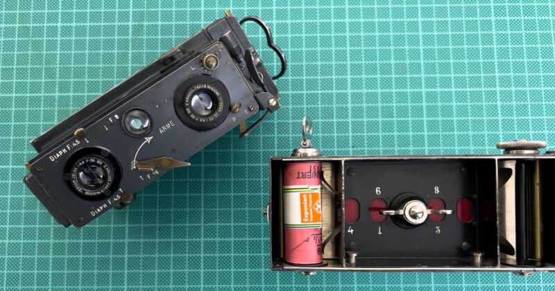 Two vintage cameras are displayed on a green grid background. The left camera shows two lenses and various settings. The right camera is open, revealing a roll of film inside.