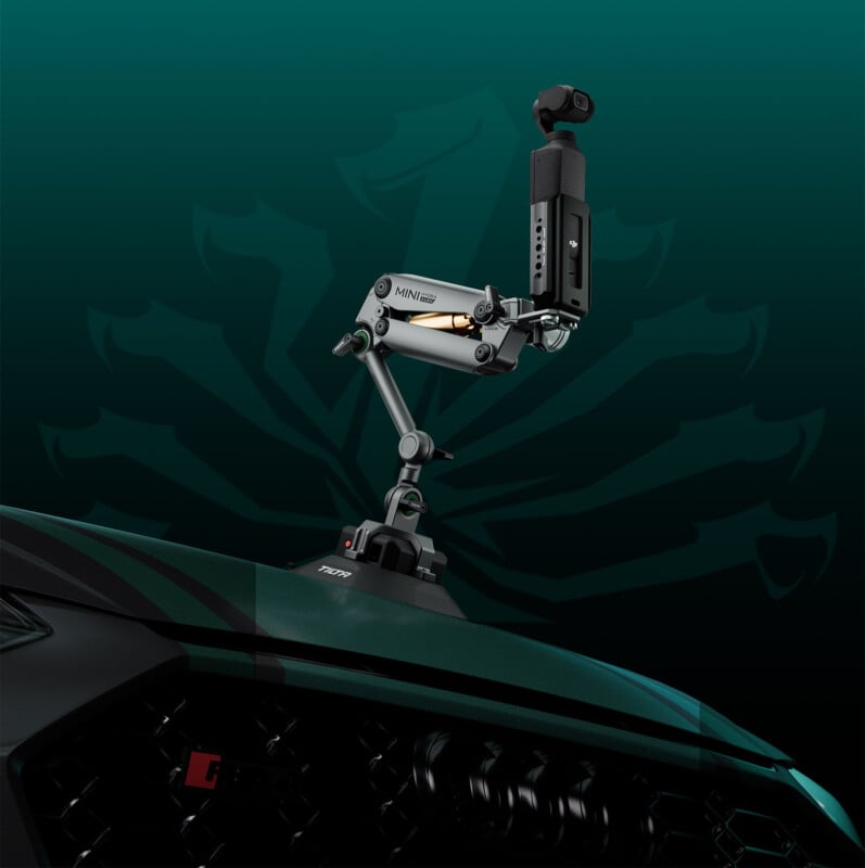 A high-tech camera mounted on a mechanical arm is attached to the front of a green vehicle, possibly for recording or monitoring. The background features a dark green gradient with a subtle emblem, creating a sleek and futuristic look.